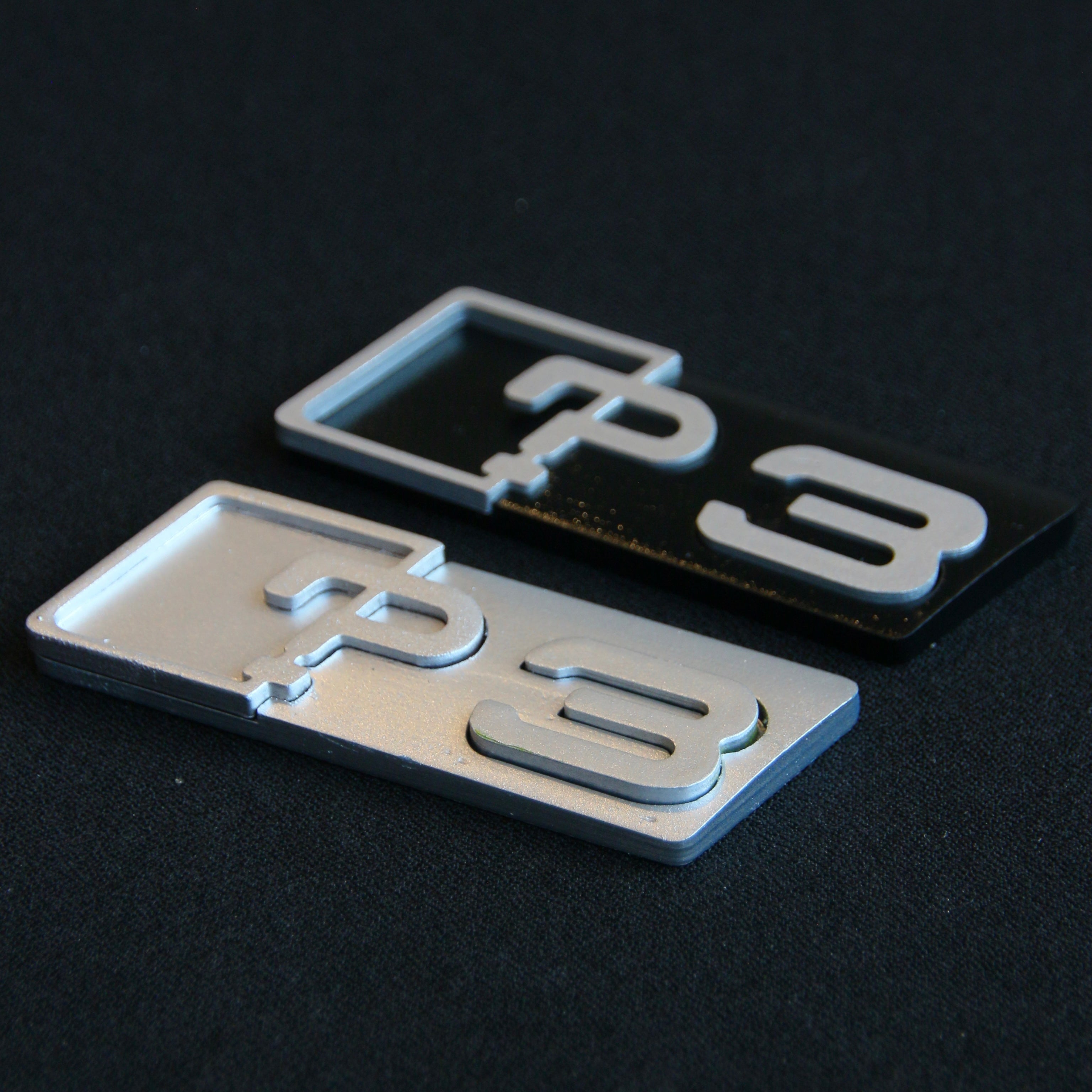 Close-up of a CHIMERA STUDIO 3 Series Badge Upgrade installed on a vehicle, showcasing sleek metallic design.